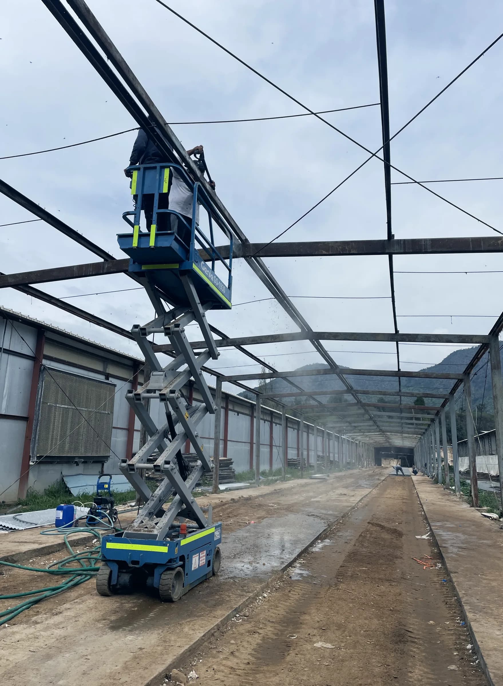 Plataforma elevadora de tijera bajo la estructura metálica durante el hidrolavado