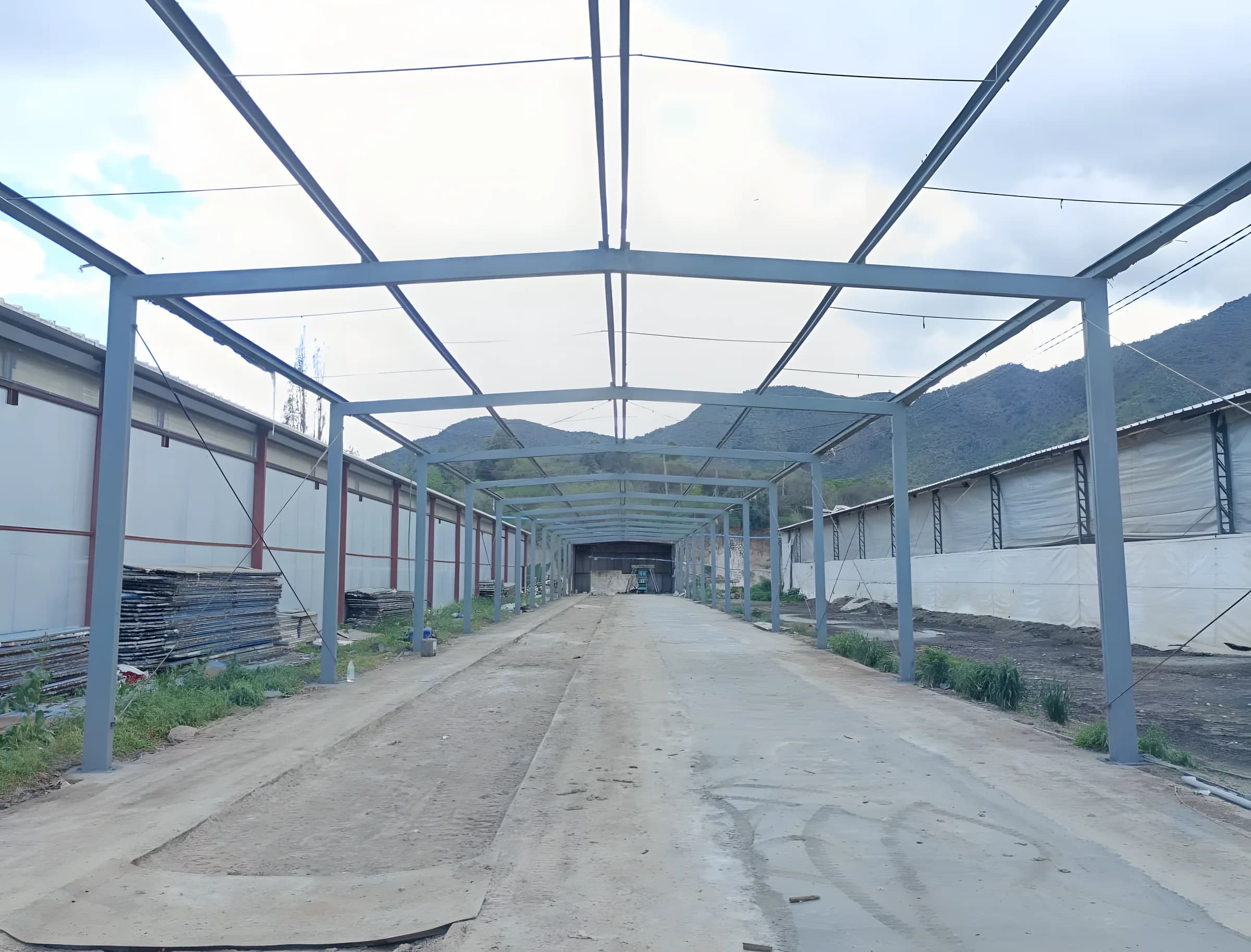 Estructura metálica de pasillo recuperada y pintada en gris azulado, con cerros al fondo